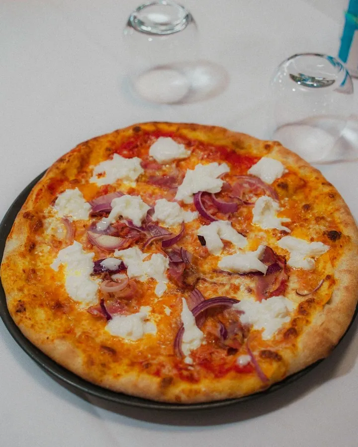 Pizza con cipolla rossa e fiocchi di formaggio filante, appena sfornata